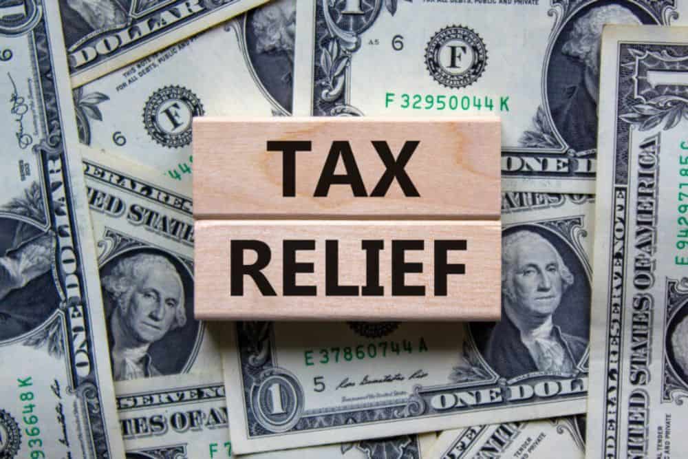 Tax relief printed on wooden blocks on a beautiful background of dollar bills