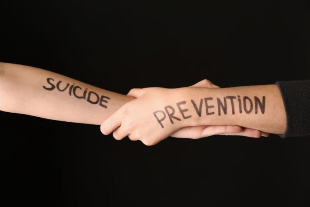 Female hands with text SUICIDE PREVENTION on dark background